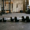 4種類の重量違いのダンベルがジムの床に並べて置かれてる画像