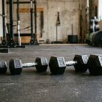 4種類の重量違いのダンベルがジムの床に並べて置かれてる画像