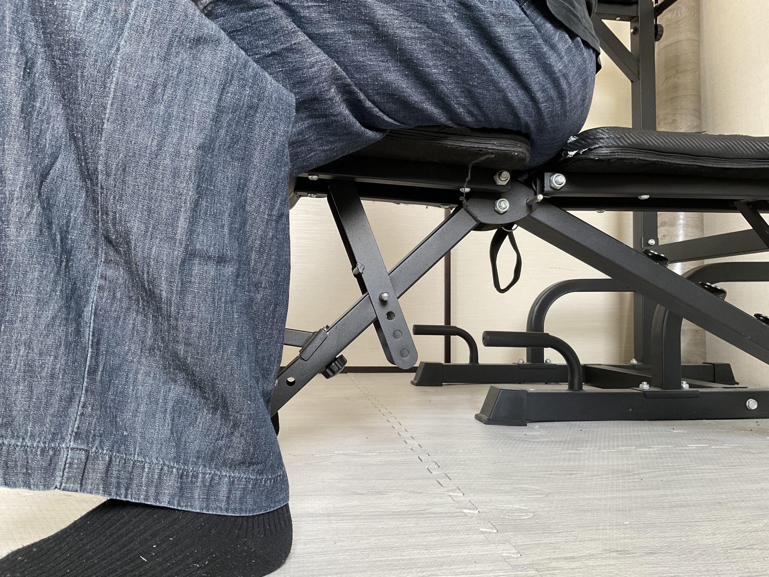 FLYBIRDトレーニングベンチの座面に腰掛けた際の足付きや、床から座面までの高さがわかる使用イメージ。